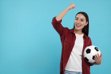 Happy fan holding soccer ball and celebrating on light blue background, space for text