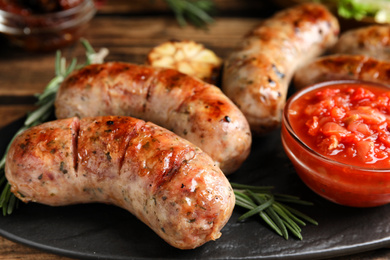 Photo of Tasty grilled sausages served on table, closeup