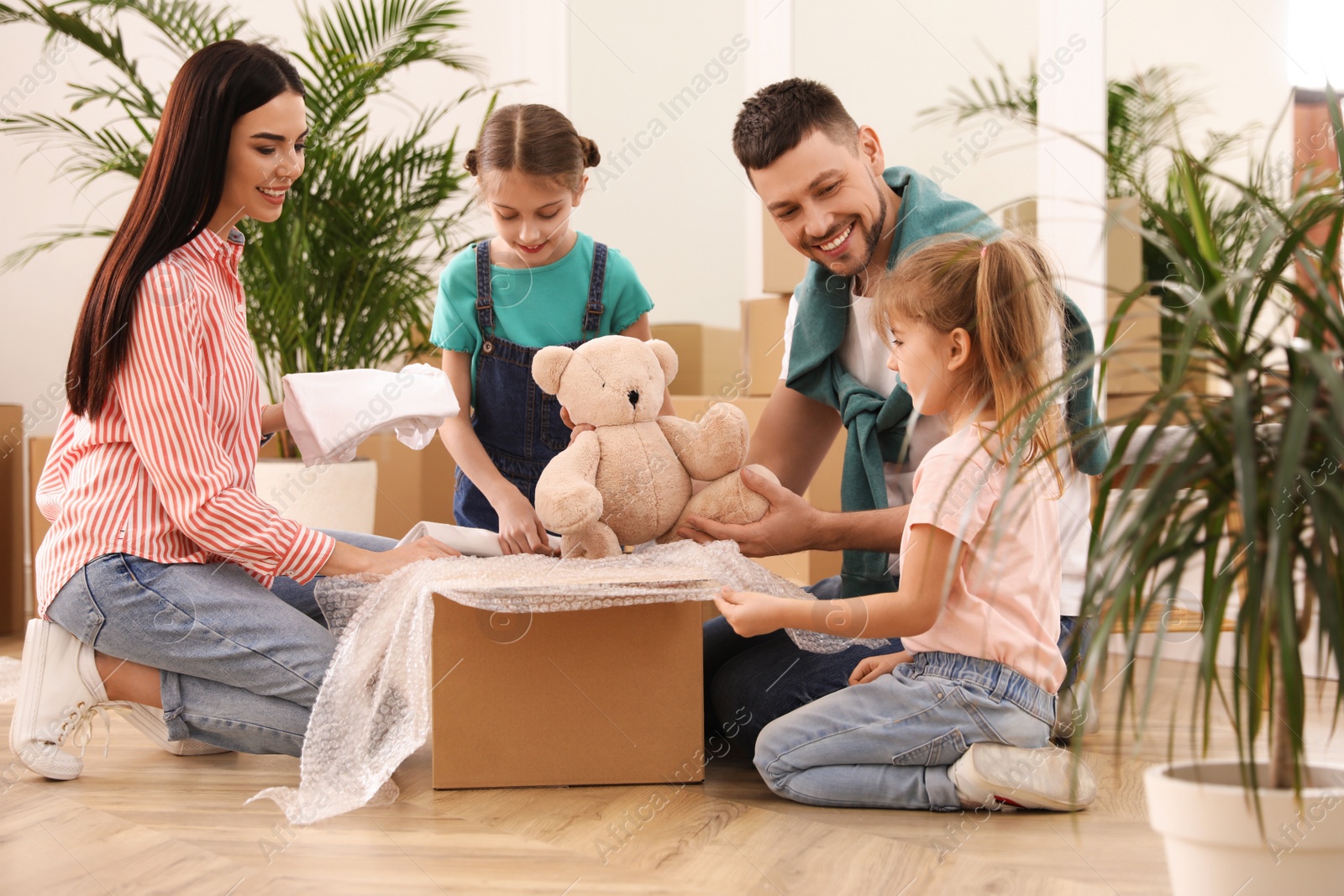 Photo of Happy family unpacking moving box in new house