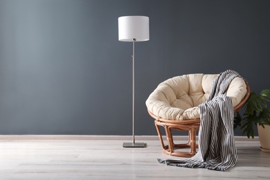 Comfortable armchair and white floor lamp against dark wall
