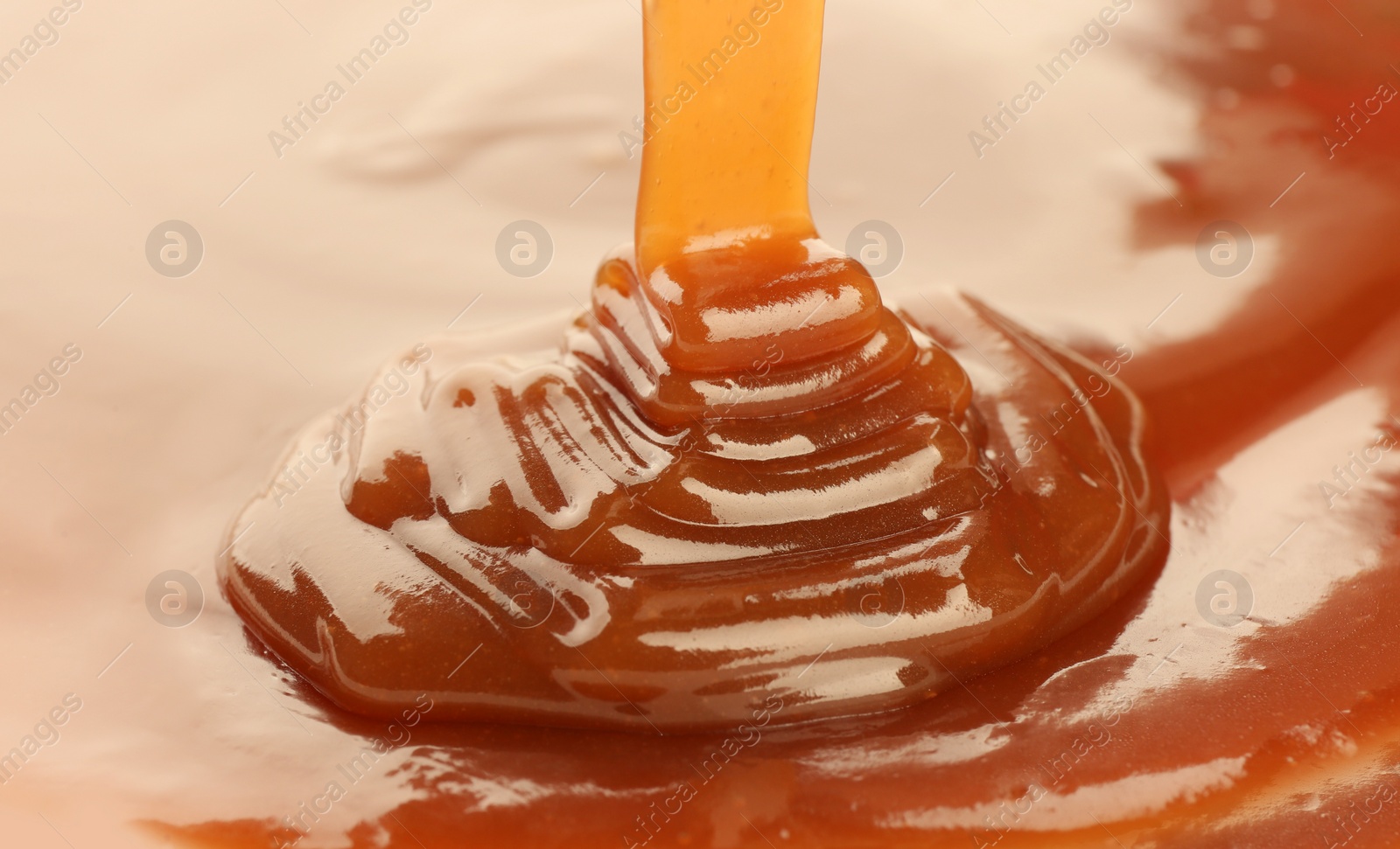 Photo of Pouring delicious caramel sauce as background, closeup