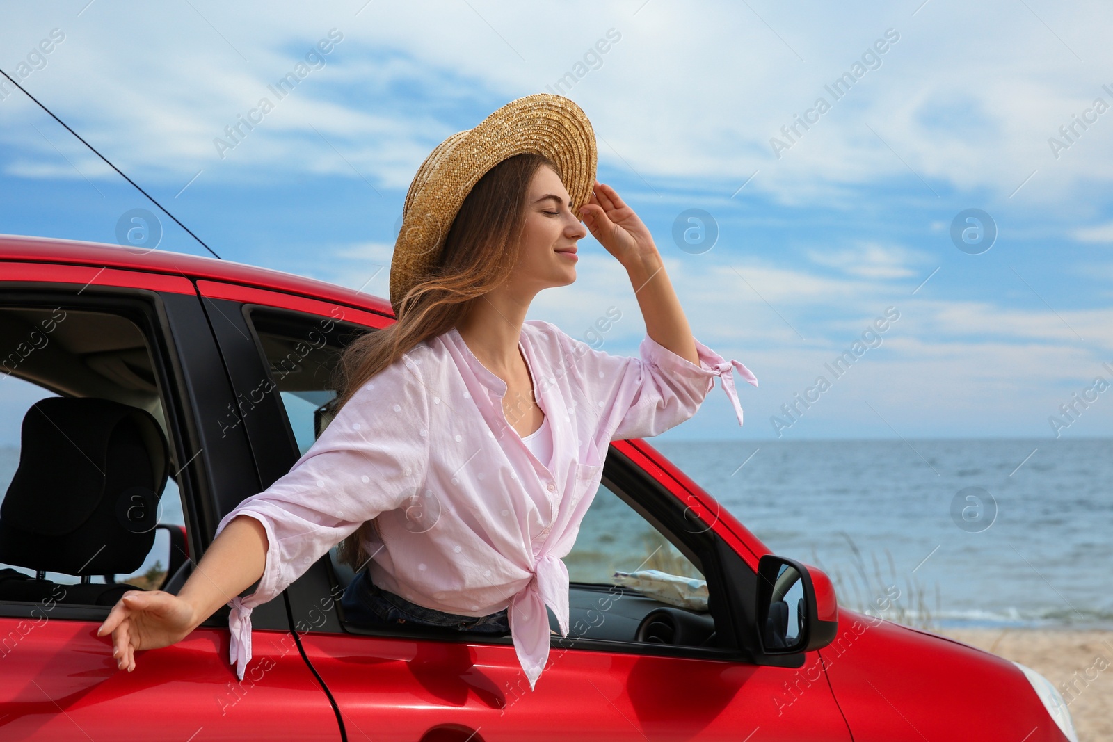 Photo of Happy woman leaning out of car window on beach. Summer vacation trip