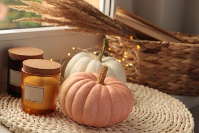 Photo of Pumpkins and scented candles on window sill