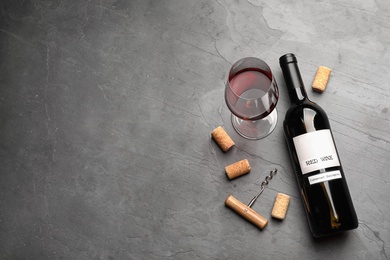 Flat lay composition with delicious red wine and corks on grey table. Space for text