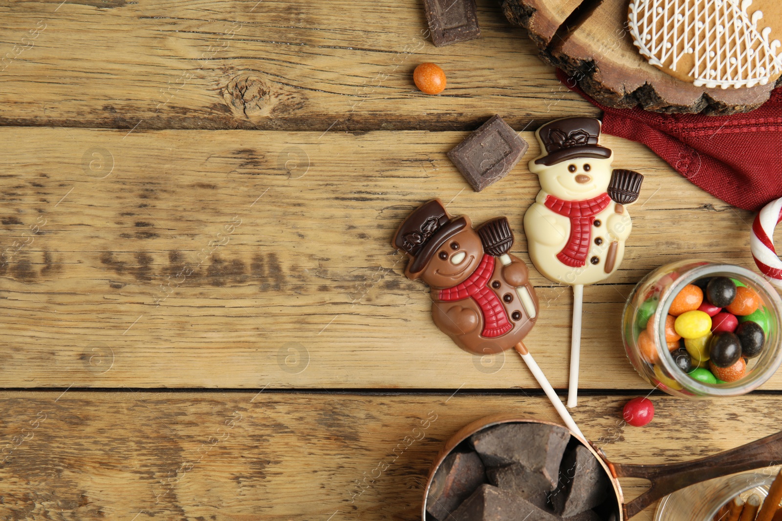 Photo of Flat lay composition with funny chocolate snowmen candies on wooden table. Space for text