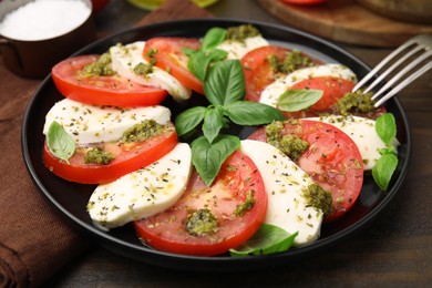 Photo of Plate of delicious Caprese salad with pesto sauce on wooden table, closeup