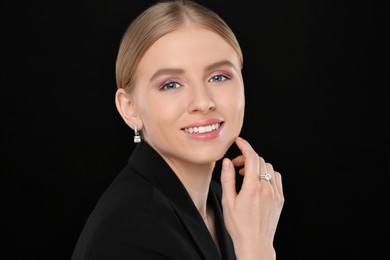 Beautiful young woman with elegant jewelry on black background