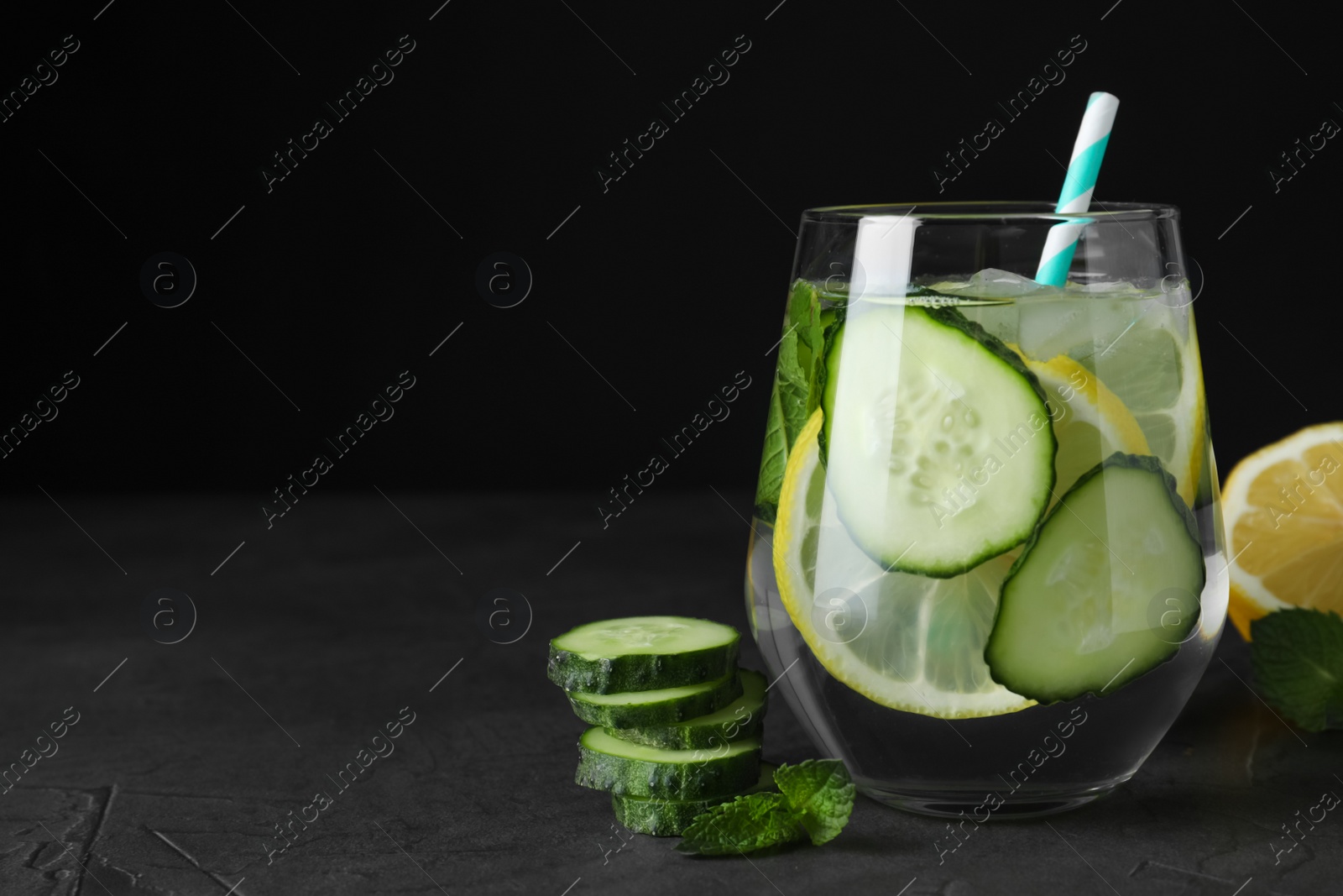 Photo of Refreshing water with cucumber, lemon and mint on black table. Space for text