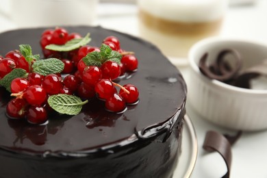 Photo of Tasty homemade chocolate cake with berries and mint on white table, closeup