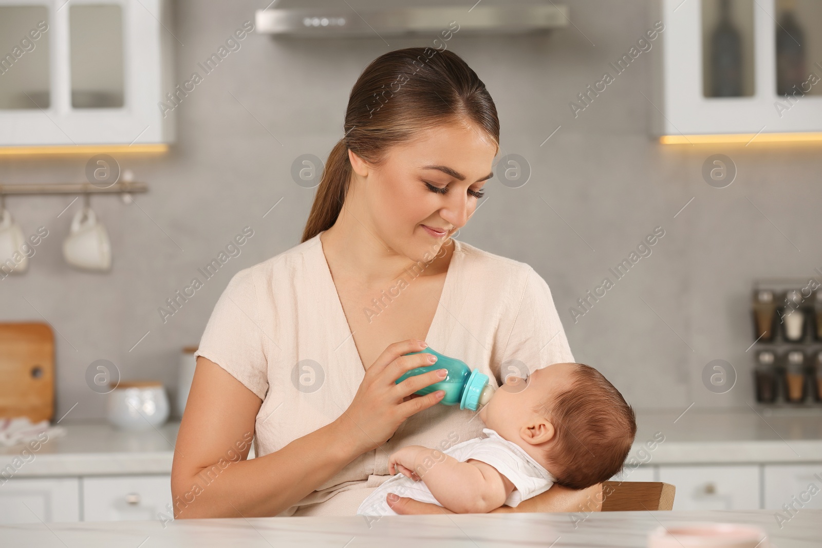 Photo of Mother feeding her cute child with infant formula indoors