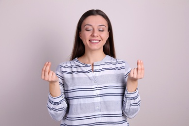 Photo of Young woman meditating on light background. Stress relief exercise