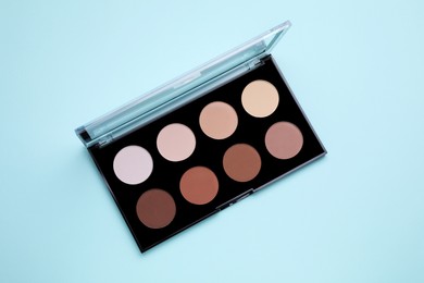 Photo of Colorful contouring palette on light blue background, top view. Professional cosmetic product
