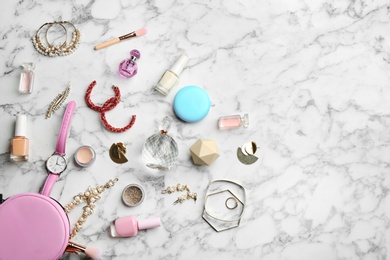 Flat lay composition with perfume bottles, jewelry and decorative cosmetics on white marble table, space for text