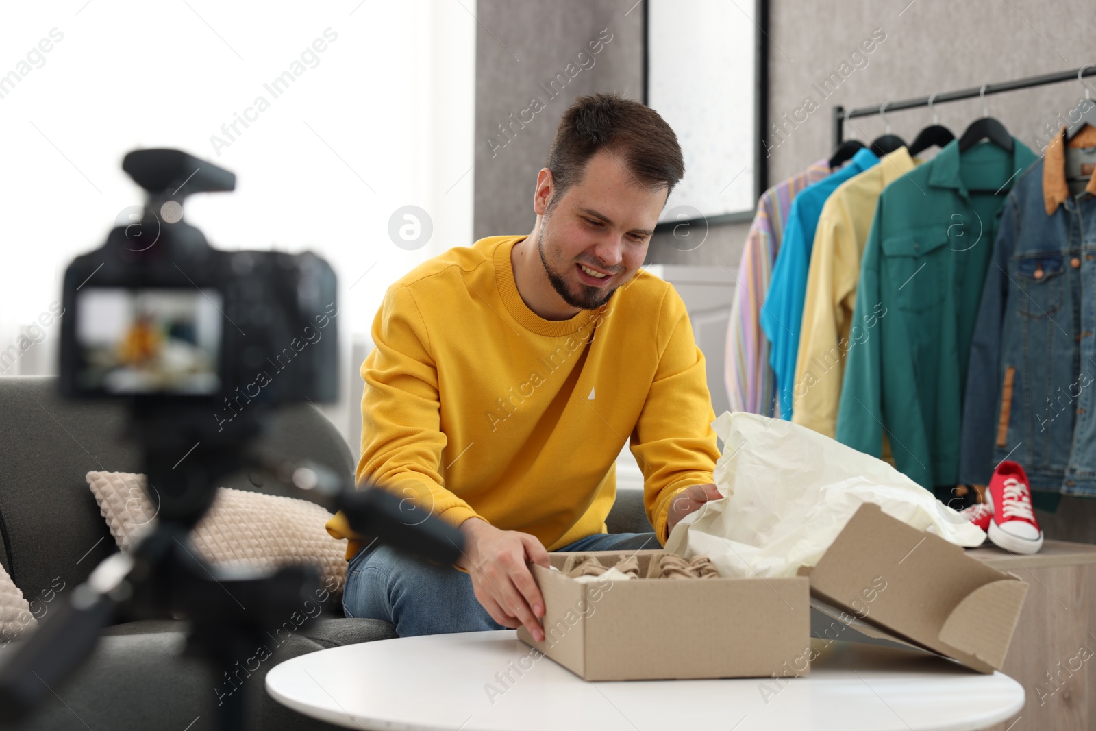 Photo of Smiling fashion blogger with parcel recording video at home