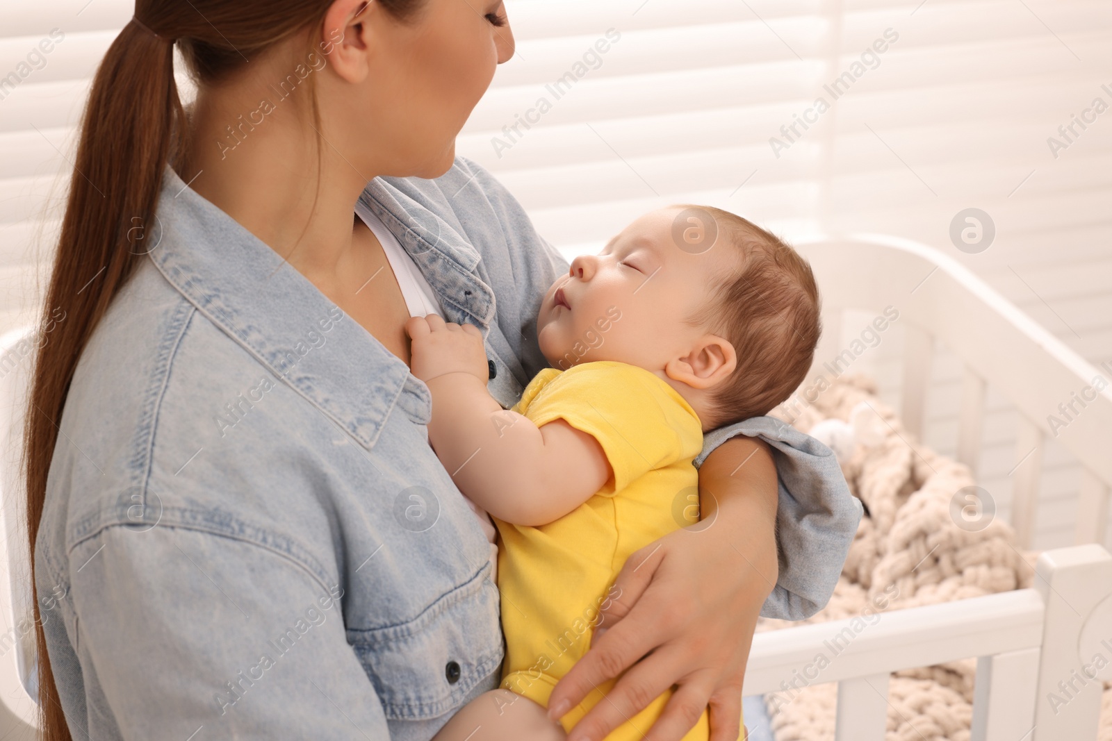 Photo of Mother holding her sleeping newborn baby at home, closeup
