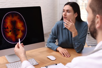 Photo of Neurologist showing brain scan to young woman in clinic