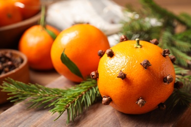 Photo of Delicious fresh tangerines with cloves on wooden table, closeup. Christmas celebration