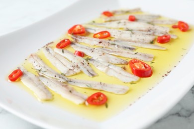 Tasty pickled anchovies with spices on plate, closeup