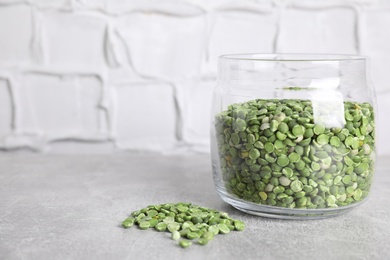 Glass jar with dry green peas on light grey table. Space for text