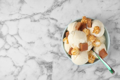 Photo of Plate of delicious ice cream with caramel candies and popcorn on white marble table, top view. Space for text