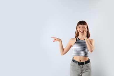 Excited girl pointing at something on white background. Space for text