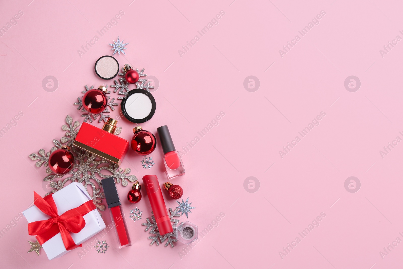 Photo of Christmas tree shape of decorative cosmetic products on pink background, flat lay with space for text. Winter care