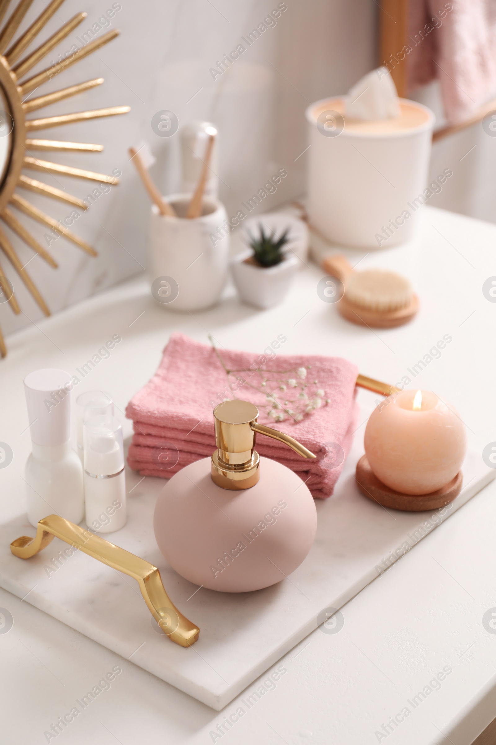 Photo of Tray with different toiletries, burning candle and towels on countertop in bathroom