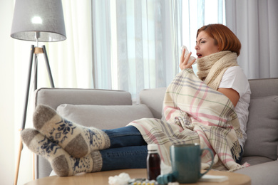 Photo of Sick woman wrapped in plaid at home. Influenza virus