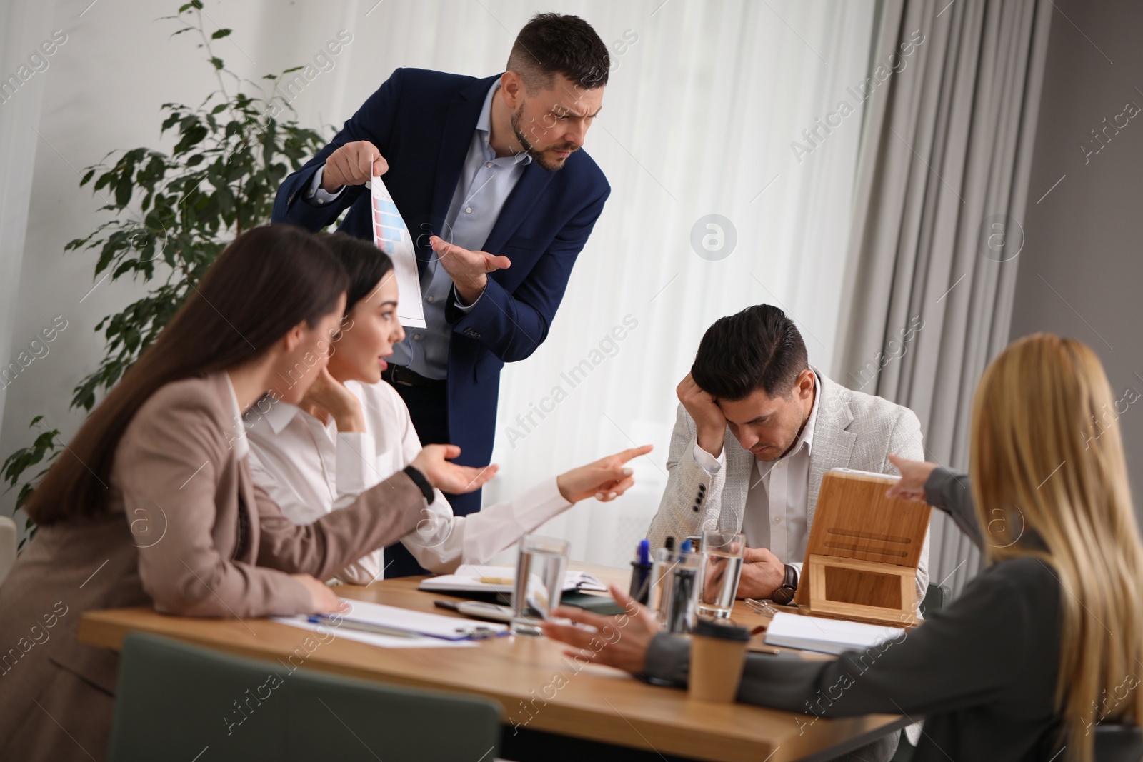 Photo of Boss scolding employee at workplace in office