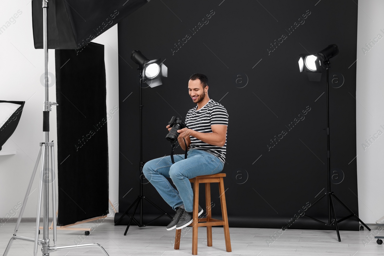 Photo of Young professional photographer with camera in modern photo studio