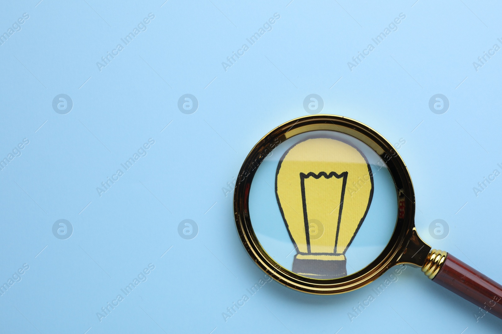 Photo of Magnifying glass over paper light bulb on blue background, top view. Space for text