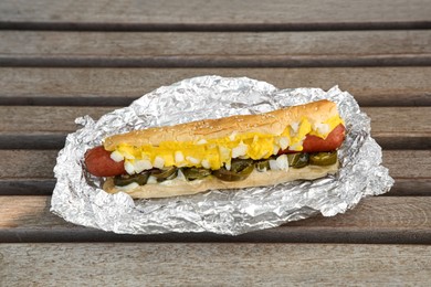 Fresh tasty hot dog with sauce on wooden surface