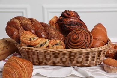 Photo of Wicker basket with different tasty freshly baked pastries on table, closeup