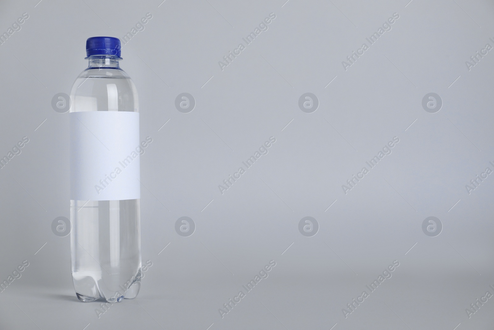 Photo of Plastic bottle with soda water on light background. Space for text