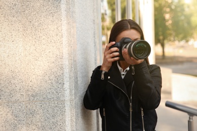 Private detective with camera spying near building on city street