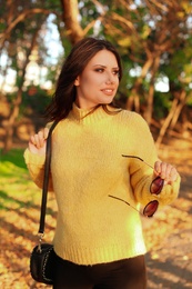 Photo of Beautiful young woman wearing stylish sweater in autumn park