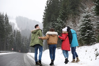 Photo of Group of friends walking near snowy forest. Winter vacation