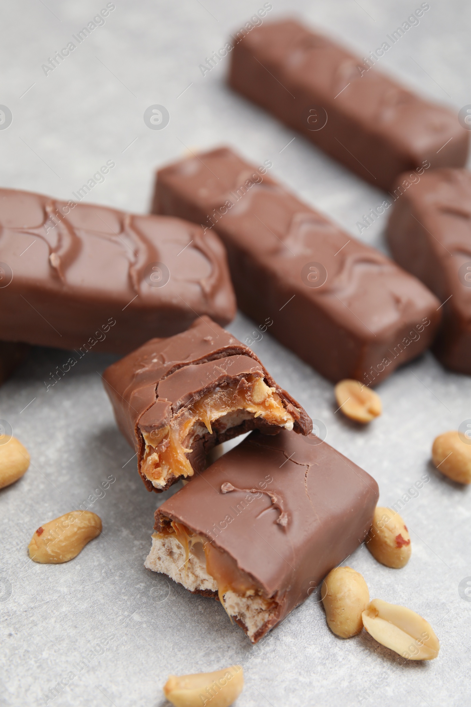 Photo of Chocolate bars with caramel, nuts and nougat on light grey table