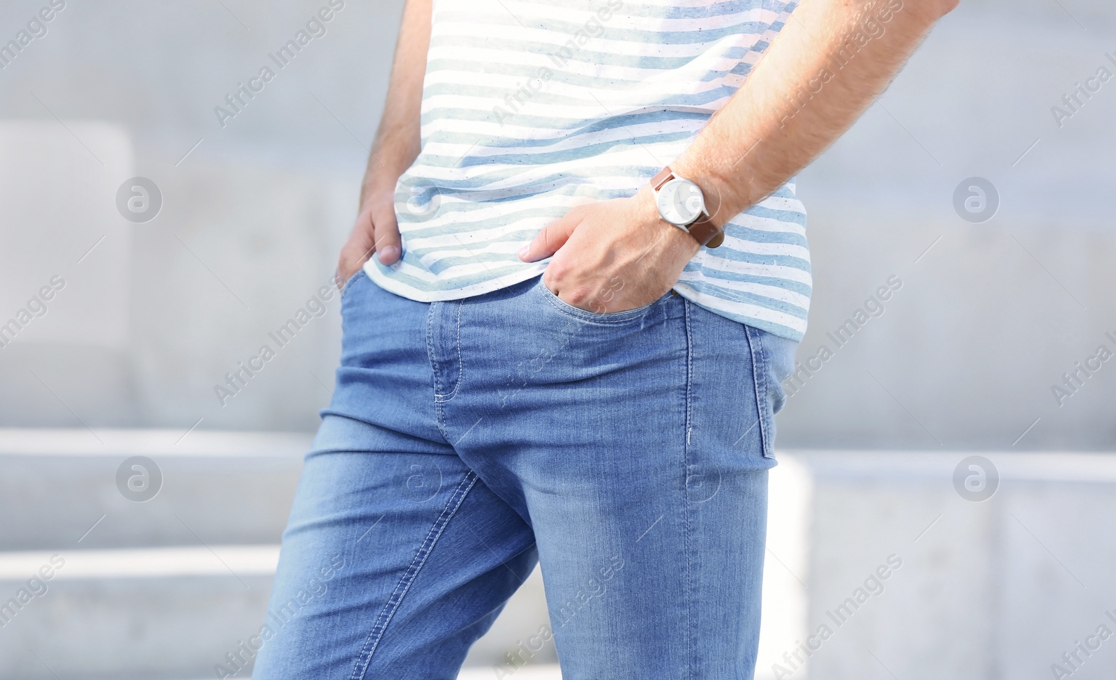 Photo of Young hipster man in stylish jeans standing near stairs outdoors