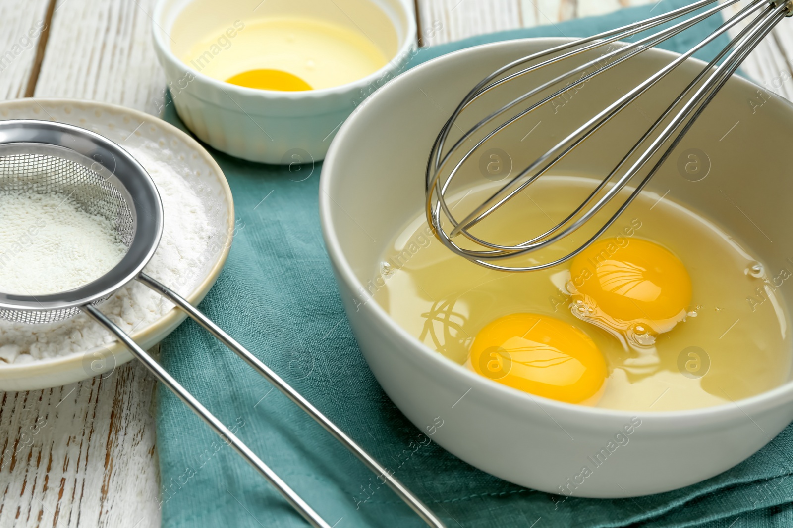 Photo of Whisking eggs in bowl on wooden table, closeup