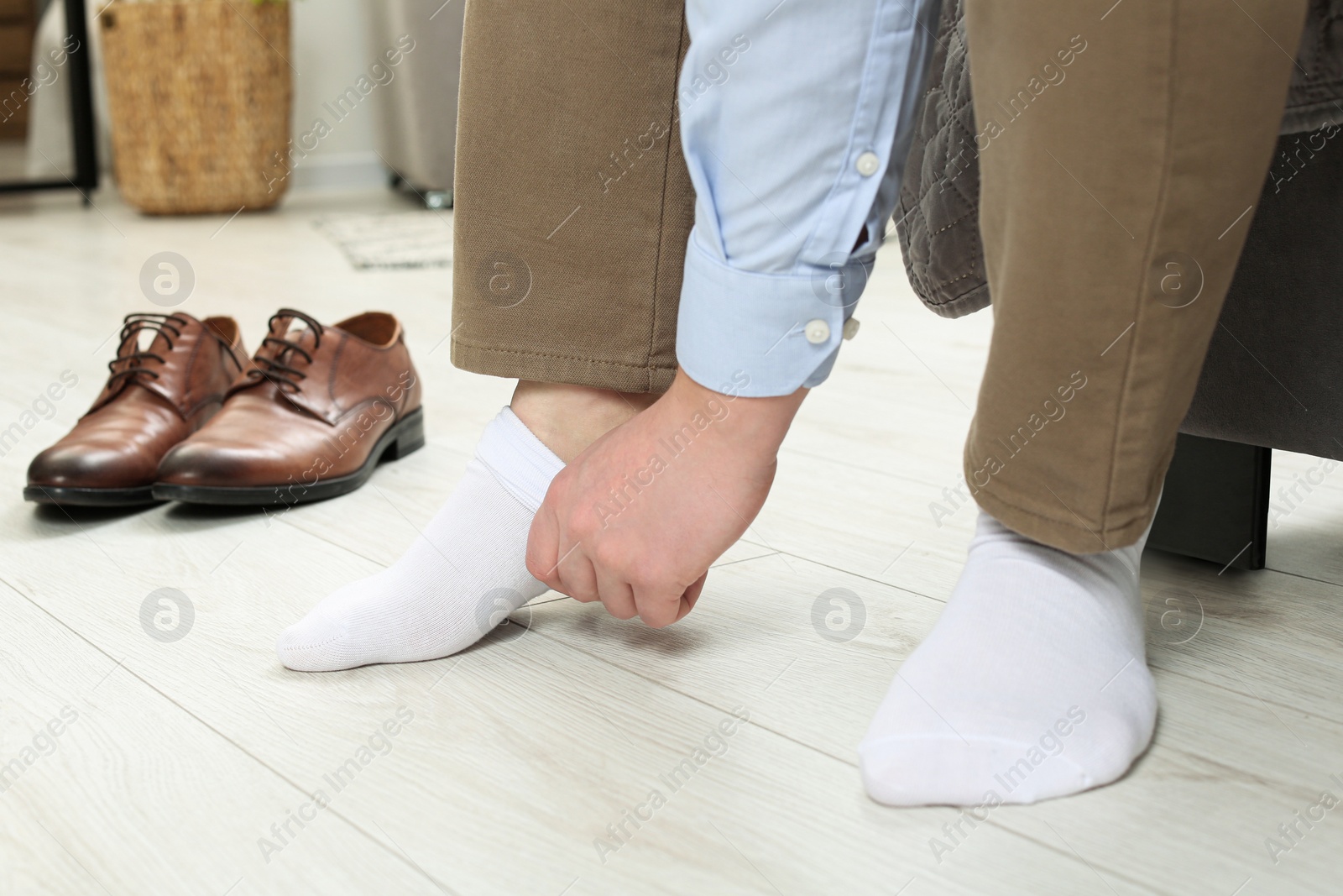 Photo of Man putting on white socks at home, closeup