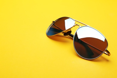 Photo of Stylish sunglasses on yellow background, space for text. Fashionable accessory