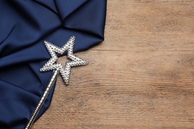 Photo of Beautiful silver magic wand and blue fabric on wooden table, top view. Space for text