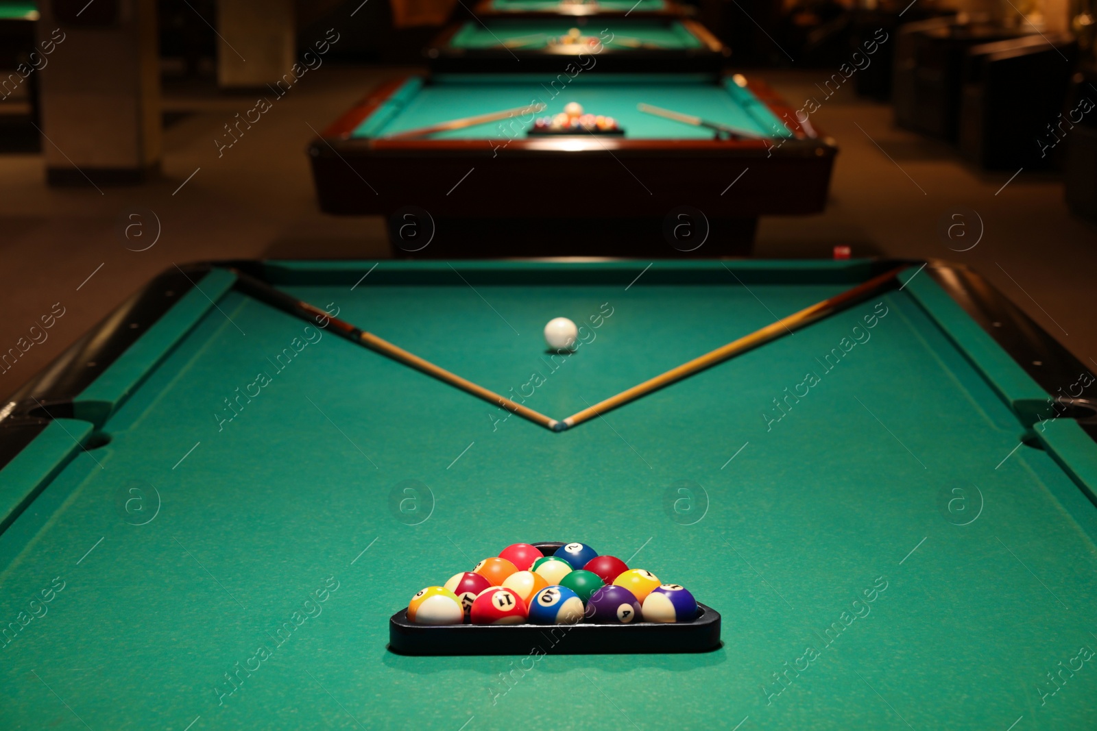 Photo of Billiard tables with balls and cues in club