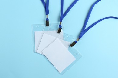 Photo of Blank badges on light blue background, flat lay. Mockup for design