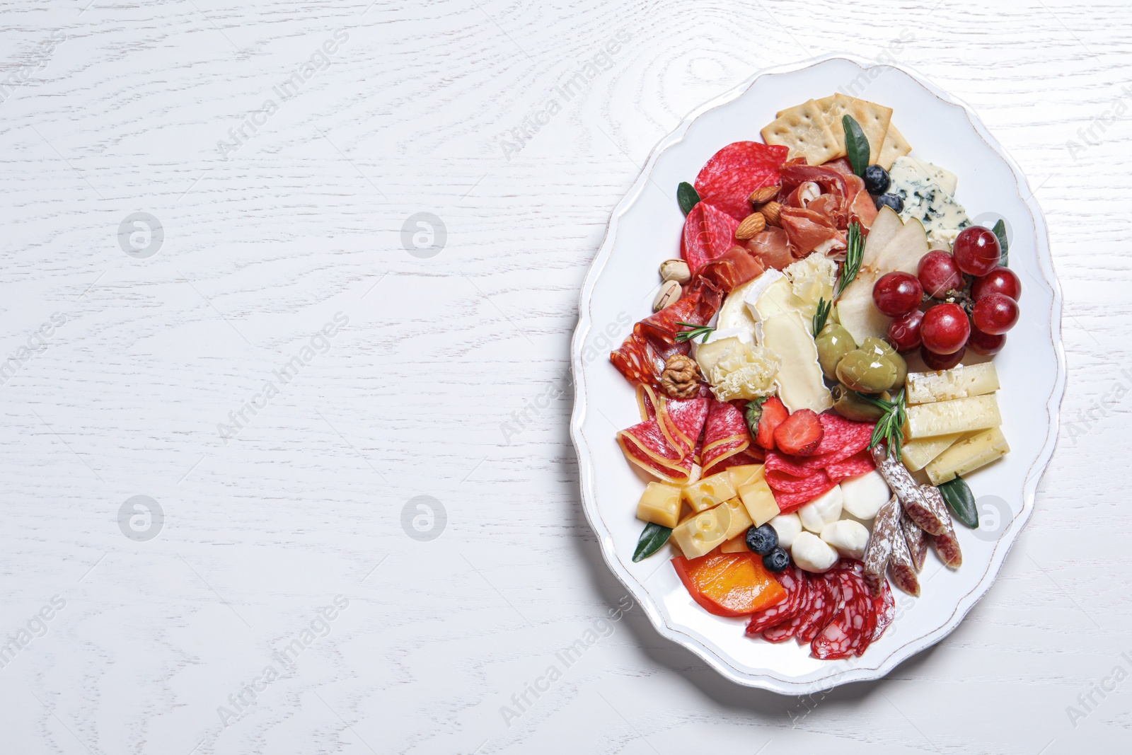 Photo of Assorted appetizers served on white wooden table, top view. Space for text