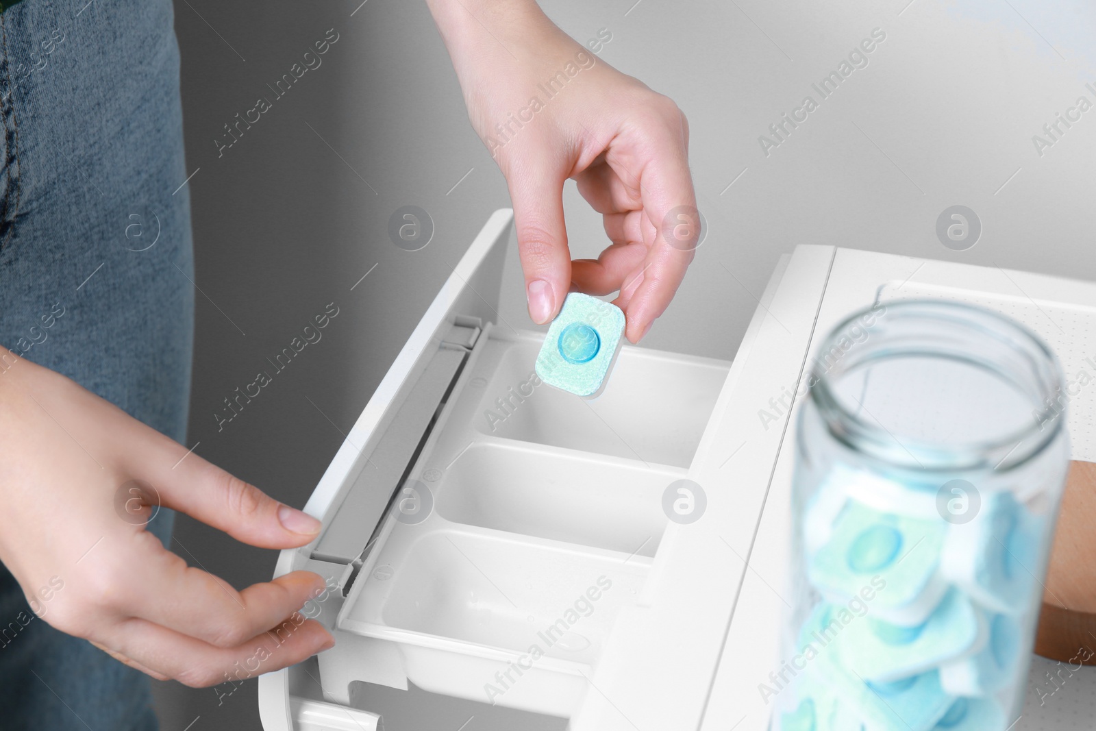 Photo of Woman putting water softener tablet into washing machine, closeup