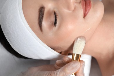 Photo of Young woman during face peeling procedure in salon, closeup