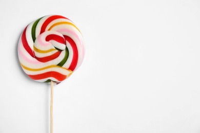 Photo of Stick with bright lollipop on white background, top view. Space for text