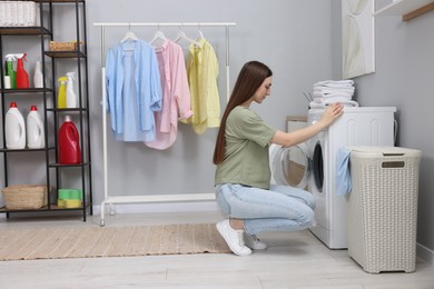 Photo of Beautiful young woman near washing machine in laundry room